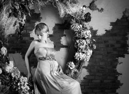 Black and white photo of a sitting pregnant woman in flower decorationsの写真素材
