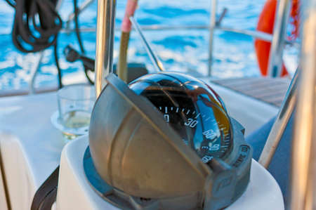 Sailing yacht compass. Sunny day, sky-blue sea water with reflections. without people.