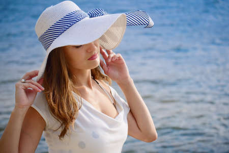 Beautiful lady in a hat on a background of waves. Warm vintage color grading and film look