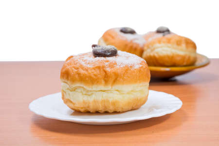 donuts on a table. in the foreground one on a plate, on a background some donuts not in focusの写真素材