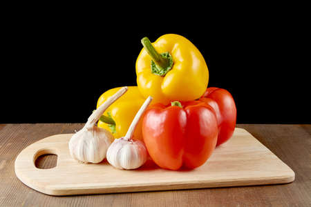 red sweet pepper and garlic on a boardの写真素材