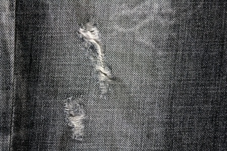 Detail of torn Black denim, front view  jean  background or textureの写真素材
