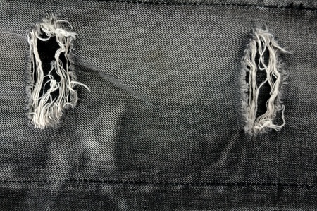 Detail of torn Black denim, front view  jean  background or textureの写真素材