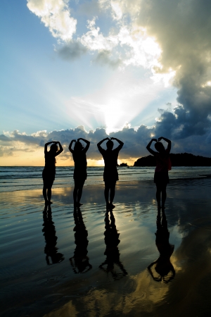 Romantic four young woman couple making heart shape with arms on beach at sunset  beautiful sky.の写真素材