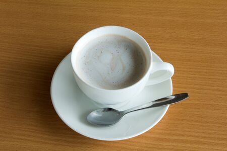 A cup of hot chocolate with cream on a wooden textured tableの写真素材