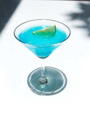 Frozen Blue Margarita Cocktail in martini glass with lemon isolated on wood tableの写真素材