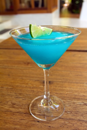 Frozen Blue Margarita Cocktail in martini glass with lemon isolated on wood tableの写真素材