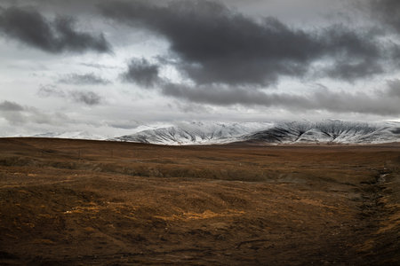 Snowy mountains and land in cloudy weatherの写真素材