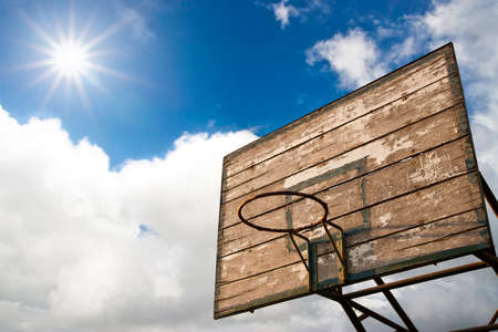 Grunge wooden basket hoop against sunrise on cloud blue skyの写真素材