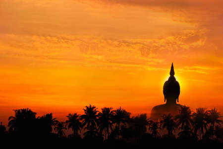 Big image buddha statue behind palm tree in sunset backgroundの写真素材