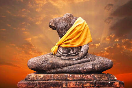 Ancient buddha statue against sunset backgroundの写真素材