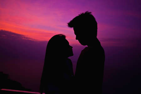 A couple getting ready to kiss each other by sunset backgroundの写真素材