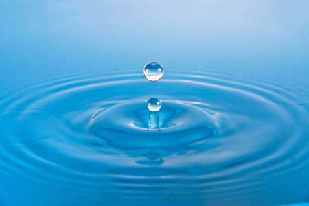 Doplets splash on clear blue waterの写真素材