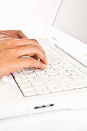 Hands typing on a white notebook keyboardの写真素材