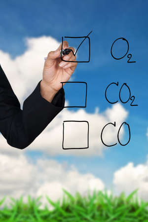 Hand selecting O2 icon, against green grass and blue skyの写真素材