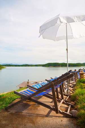 Wood chair and umbrella in resort beside dam lakeの写真素材