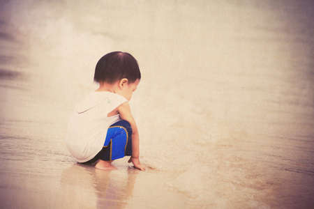 Child playing lonely on the beach, vintage styleの写真素材