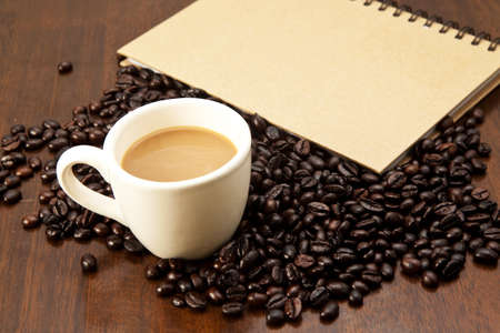 Coffee cup and beans with book on the tableの写真素材