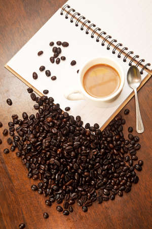 Cup of coffee on the book with beansの写真素材