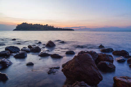 Sunset againt rock on sea beachの写真素材