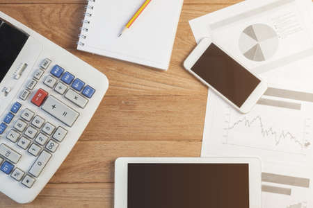 Investment charts with laptop and calculator on wooden table workplaceの写真素材
