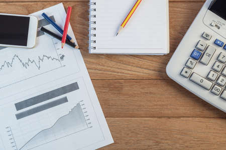 Investment charts with laptop and calculator on wooden table workplaceの写真素材