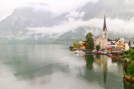 Scenic view of famous Hallstatt mountain village in the Austrian Alps with misty raining, Salzkammergut region, Austriaの写真素材