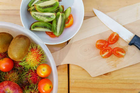 White knife with kiwi and mixed of fruits on wooden floorの写真素材