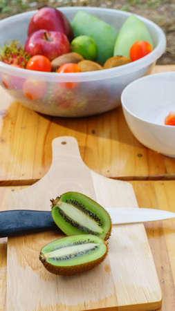 White knife with kiwi and tomato fruits on wooden floorの写真素材