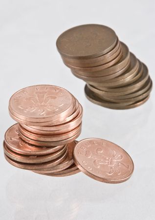 Two uneven stacks of new and tarnished English Two Pence Pieces isolated on whiteの写真素材