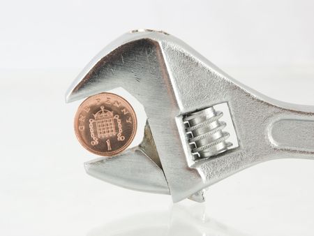 English penny coin clamped tightly in the jaws of an adjustable wrench on a reflective base isolated on whiteの写真素材