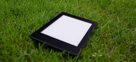 ebook reader lying on wet grass - stock photoの写真素材