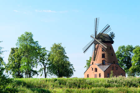 old brick windmill on field on blue sky background の写真素材