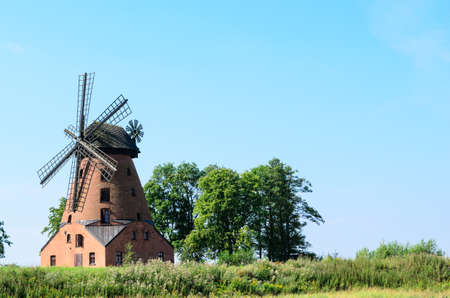 old brick windmill on field on blue sky background の写真素材