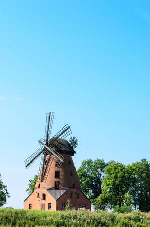 old brick windmill on field on blue sky background の写真素材