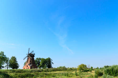 old brick windmill on field on blue sky background の写真素材