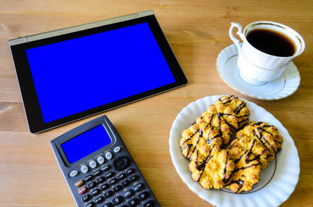 workplace with tablet pc - blue box, calculator, cup of coffee and cookies - stock photoの写真素材