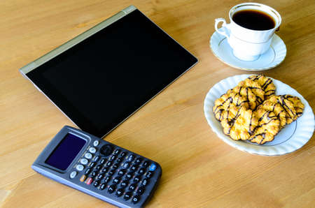 workplace with tablet pc, calculator, cup of coffee and cookies の写真素材