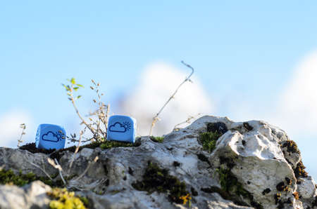 weather dice with cloud-sun sketch lying on the rock on nature background - stock photoの写真素材