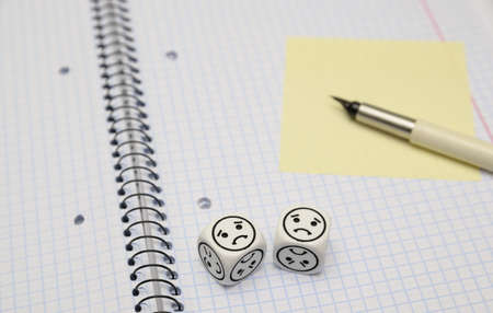 open exercise book with mood dice (sad) and yellow sticky card - stock photoの写真素材
