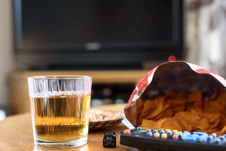 unhealthy food on table with skull dice and tv in background の写真素材