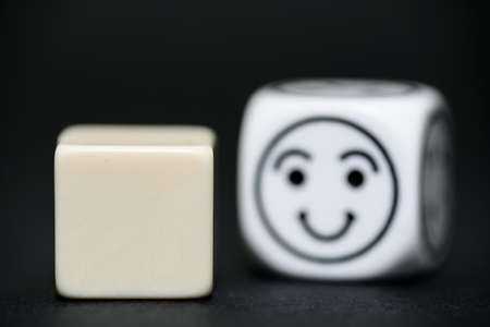 blank dice with emoticon dice (happy) in background の写真素材
