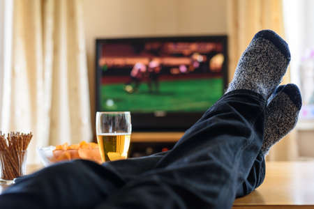 Television, TV watching (football match) with feet on table and huge amounts of snacks - stock photoの写真素材