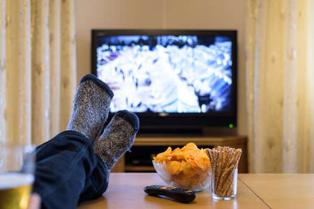 TV, television watching (refugee camp, news) with feet on the table eating snacks and drinking beerの写真素材