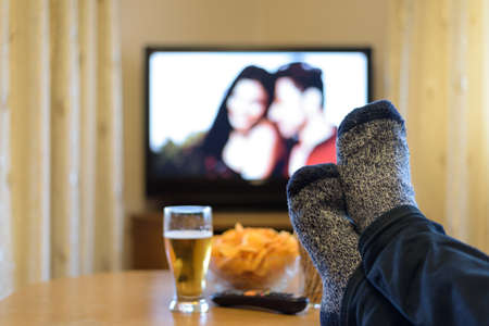 TV, television watching (romance movie) with feet on the table and snacks - stock photo