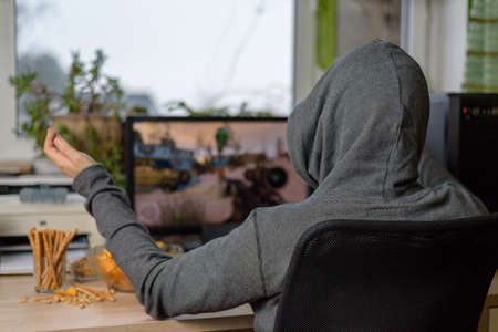 male gamer playing shooting game on computer with snacks lying on table - stock photoの写真素材