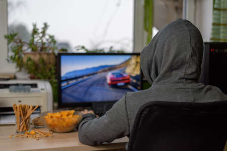 male gamer playing racing game on computer with snacks lying on table - stock photoの写真素材