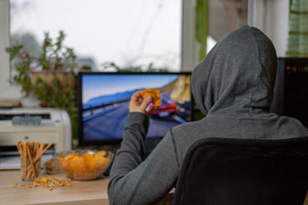 male gamer playing racing game on computer with snacks lying on table - stock photoの写真素材