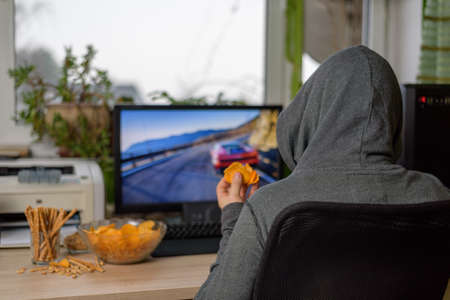 male gamer playing racing game on computer with snacks lying on table - stock photoの写真素材