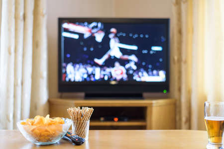 Television, TV watching (basketball game) with snacks and alcohol lying on table - stock photoの写真素材